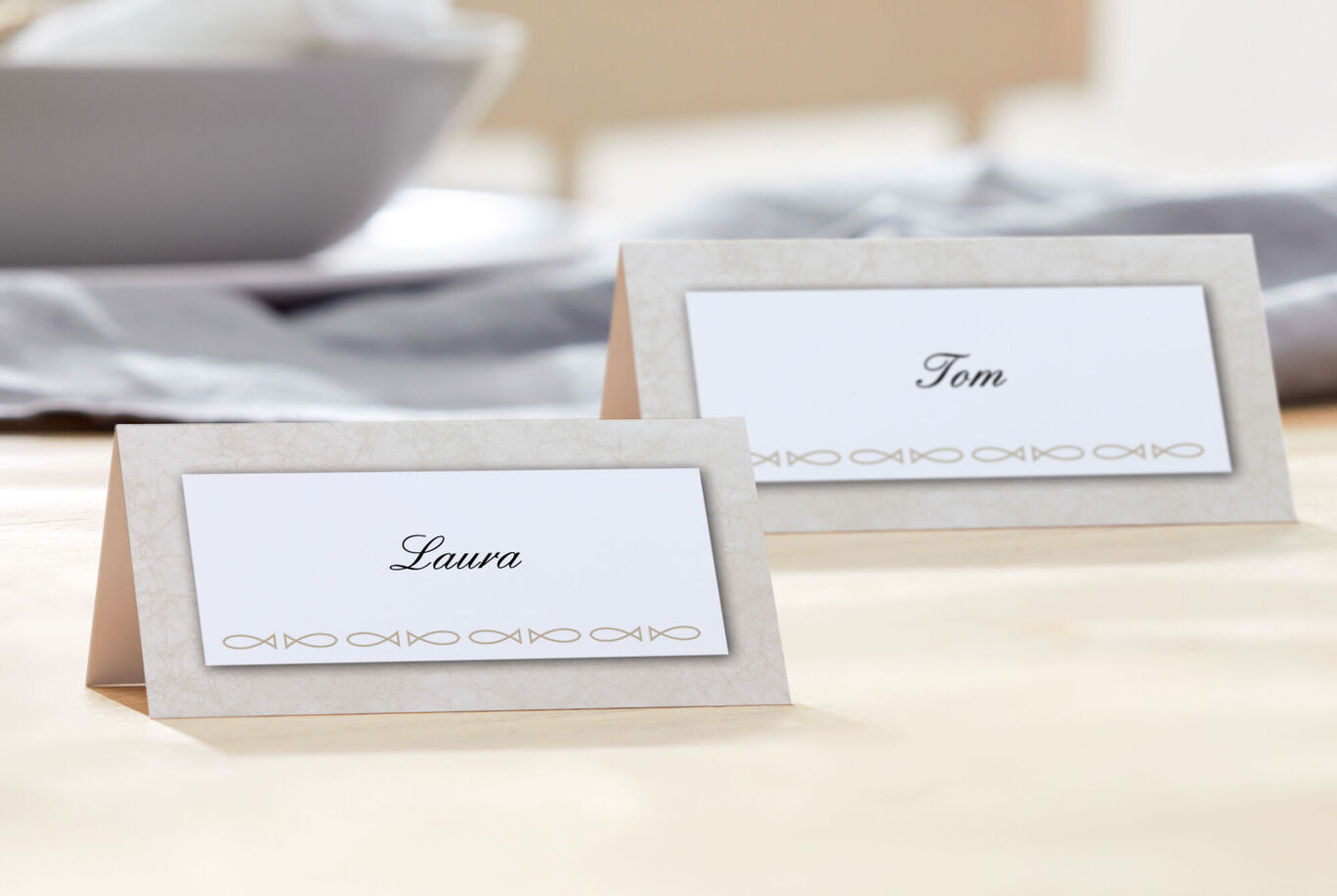 Twee tafelkaarten met de namen Laura en Tom op een lichte tafel.