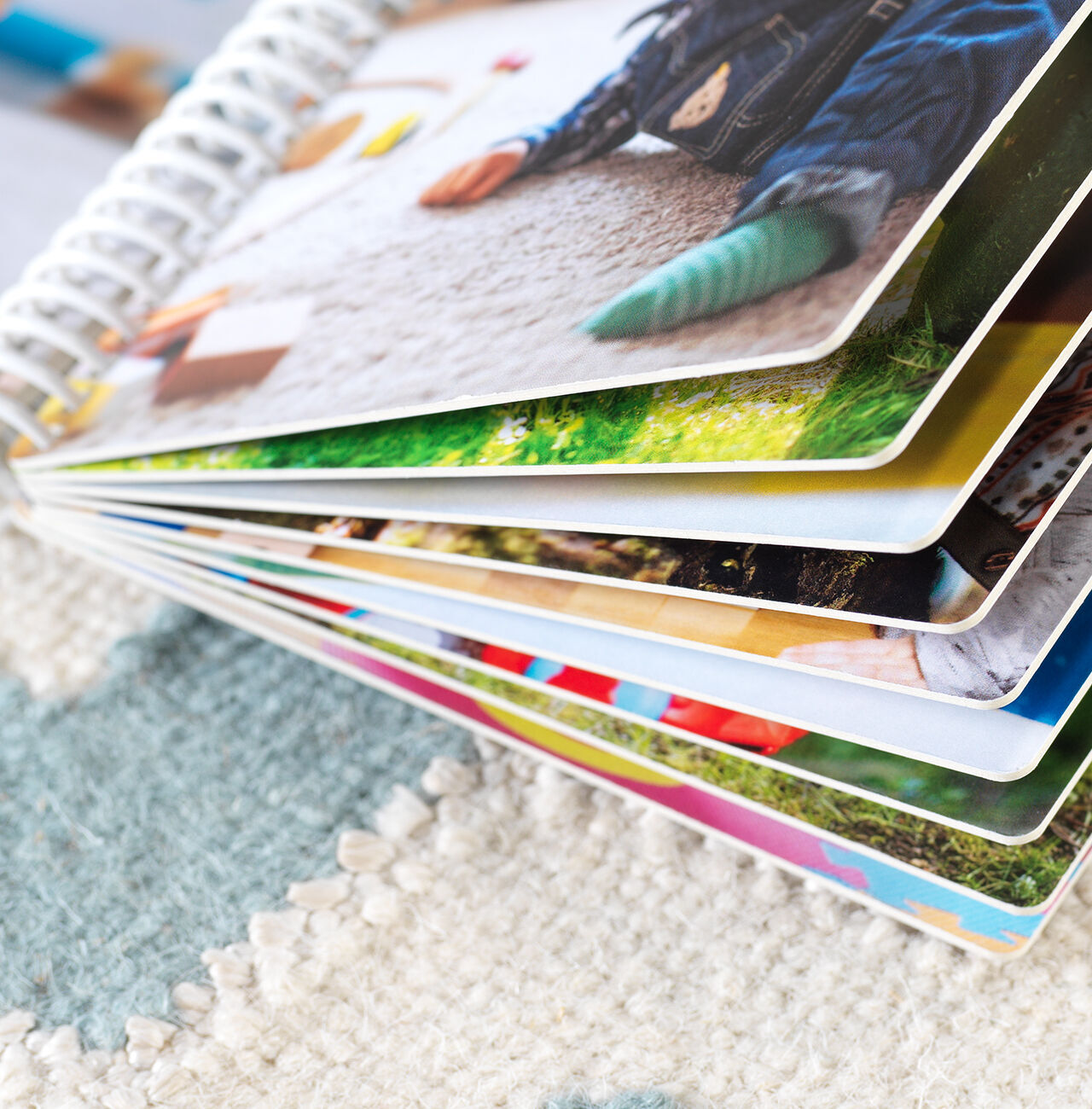 Detailweergave van een geopend fotoboek met kleurrijke pagina's, liggend op een tapijt.
