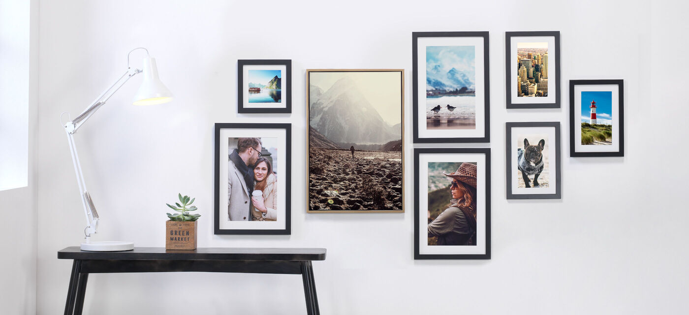 Muur met verschillende ingelijste foto's en een lamp.