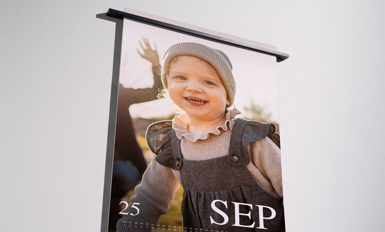Een liefdevol ontworpen fotokalender met een glimlachend kind buiten dat in de camera kijkt en wijst.