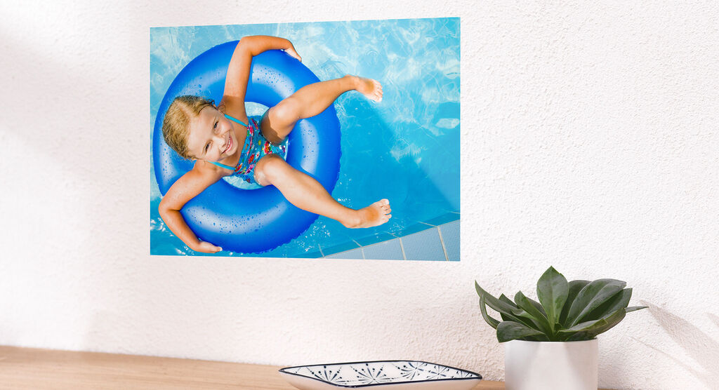 Een vrolijk meisje zit in een blauwe zwemband in het water en geniet van de zomer.