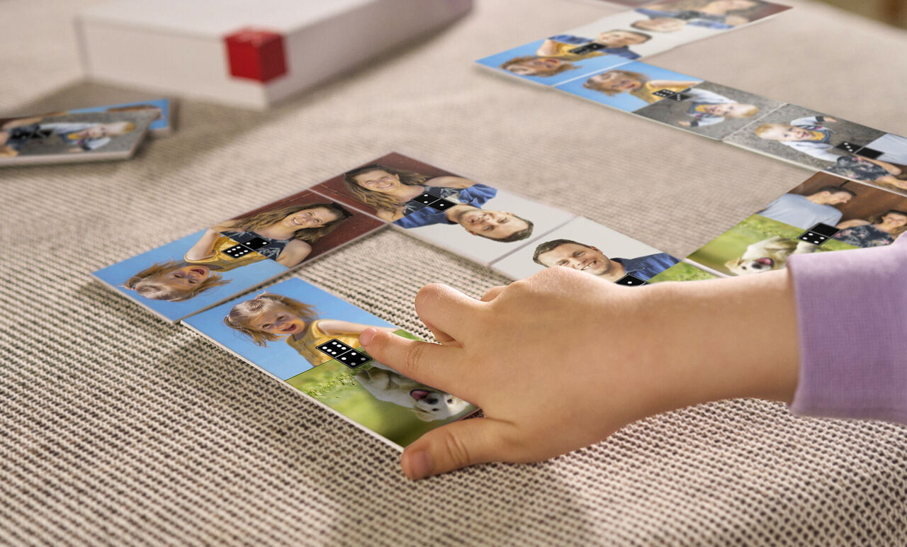 Een kind speelt met gepersonaliseerde dominostenen met foto's van vrienden en familie.