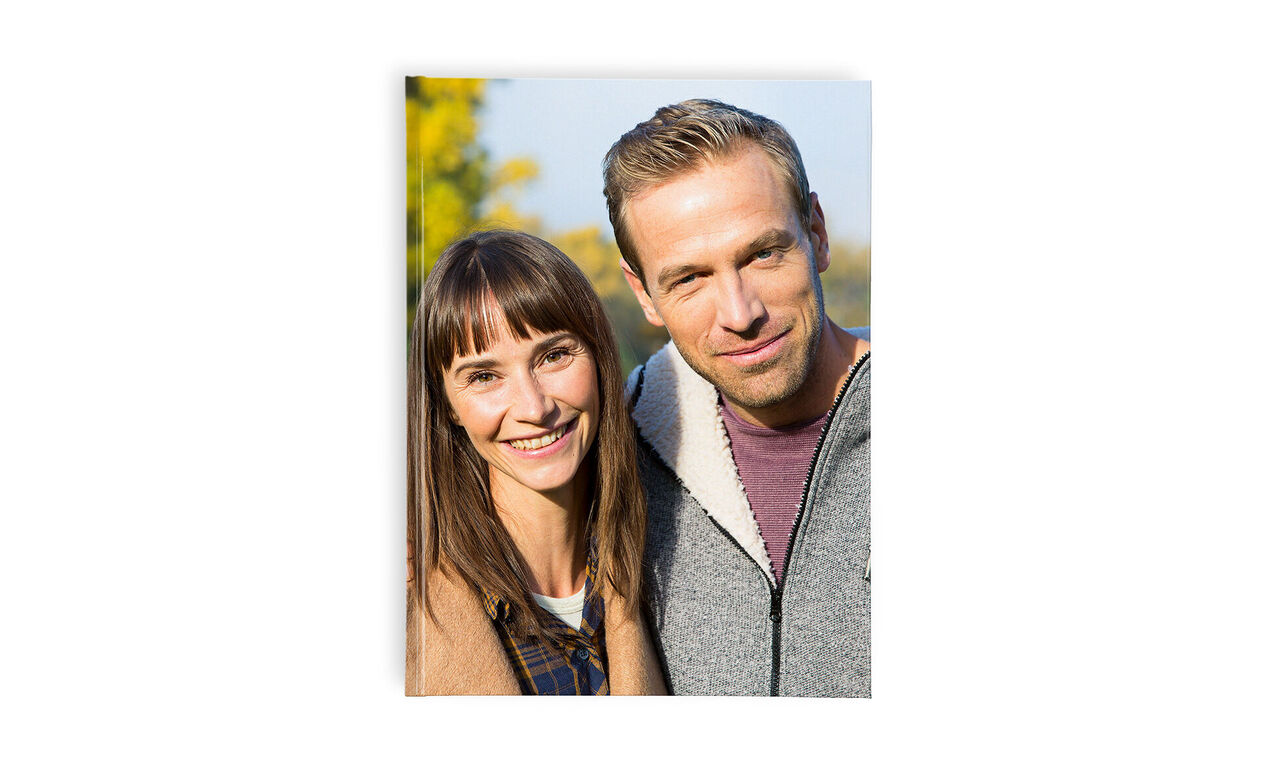 Twee mensen glimlachen in de natuur, een vrouw met lang haar en een man met een klassiek kapsel.