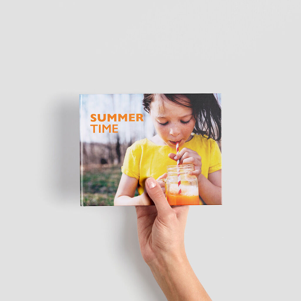 Een persoon houdt een CEWE Fotoboek met de titel 'Summer Time' in de hand.