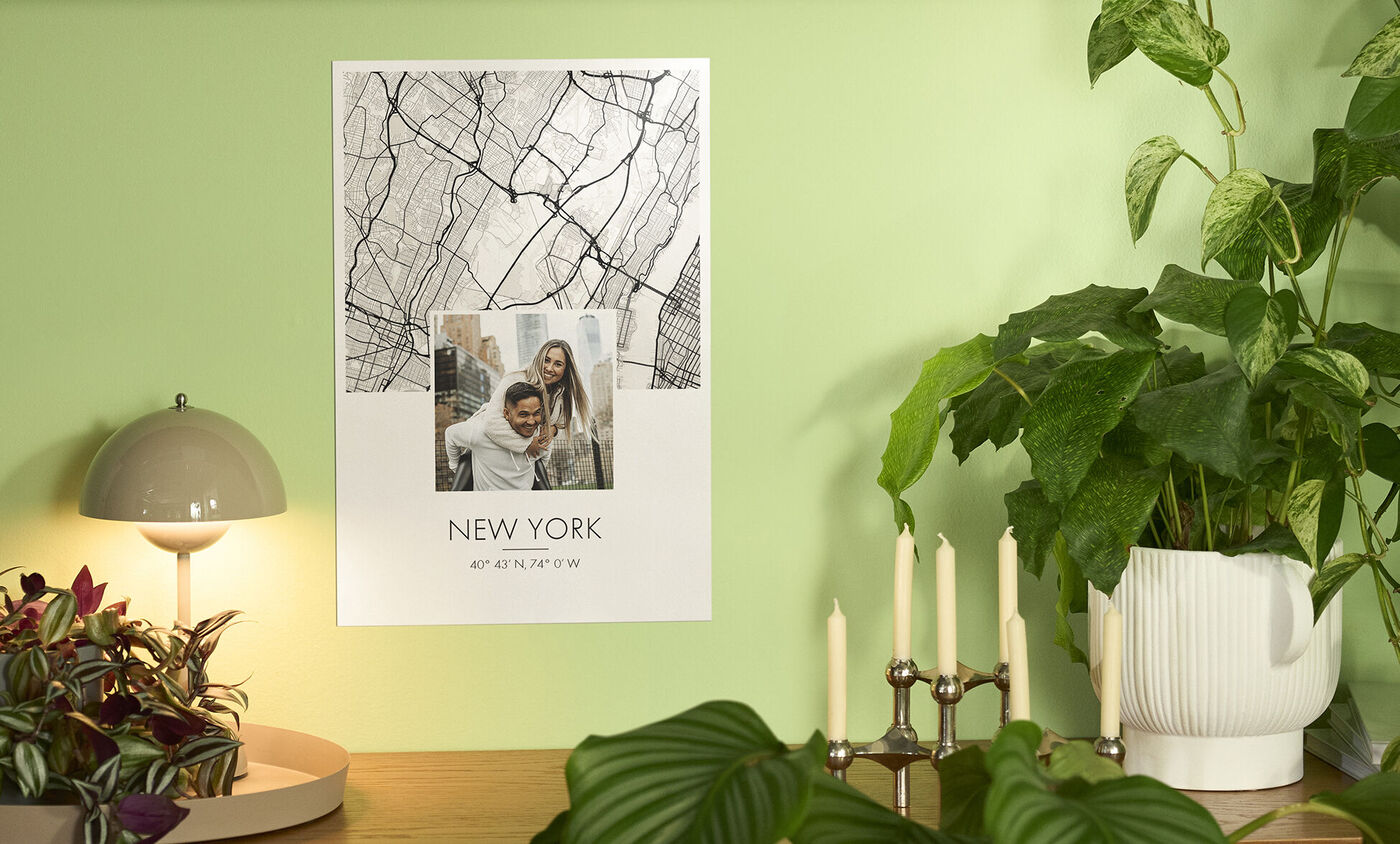 Een poster van New York hangt aan een groene muur. Het toont een scene en de tekst 'NEW YORK'.