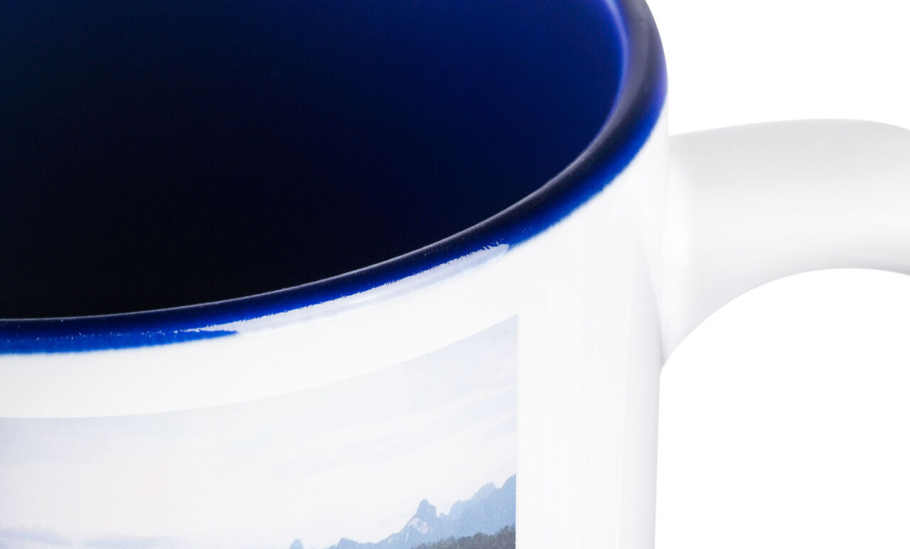 Mok met blauwe rand en foto van een bergpanorama.